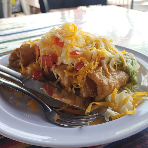 A Don Pancho Mexican Food burrito, topped with shredded cheese, diced tomatoes, and guacamole.