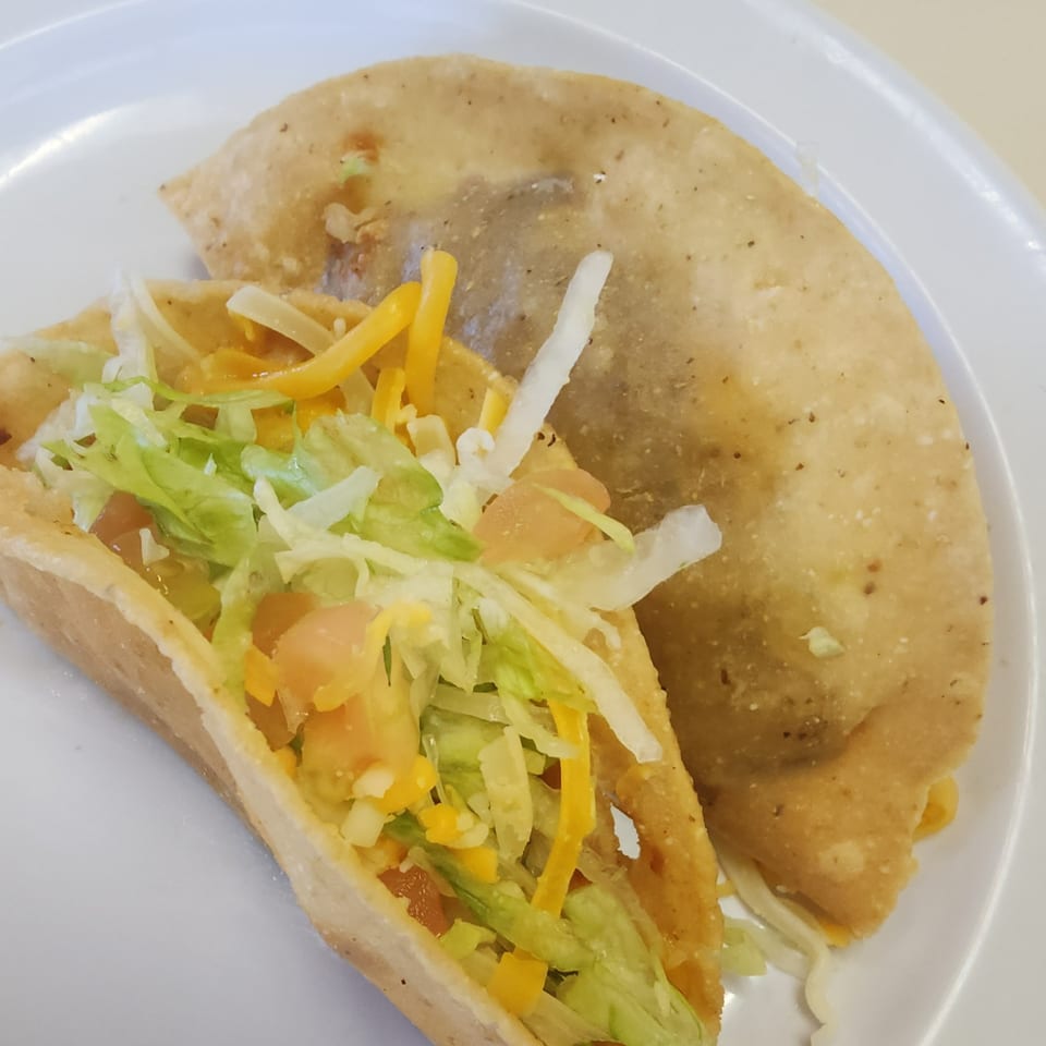 Two crispy Don Pancho Mexican tacos, one filled with lettuce, cheese, and tomatoes.