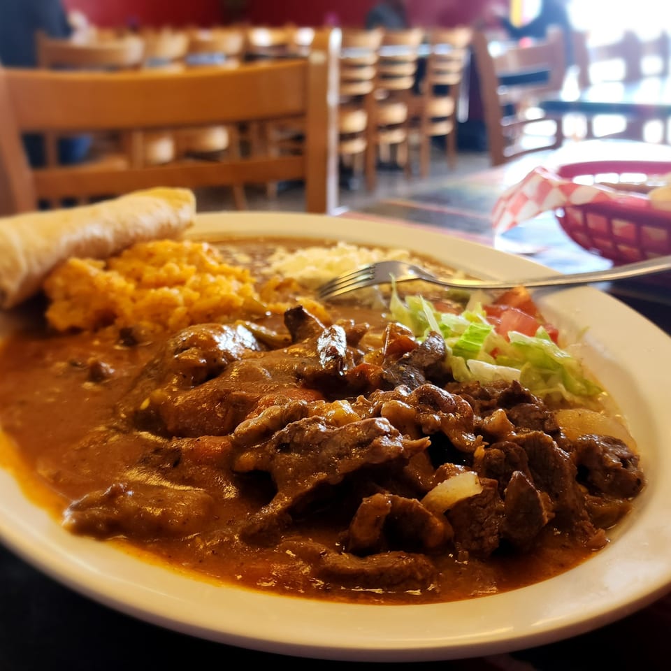 Don Pancho's Mexican food plate with beef in sauce, rice, beans, and a side salad.