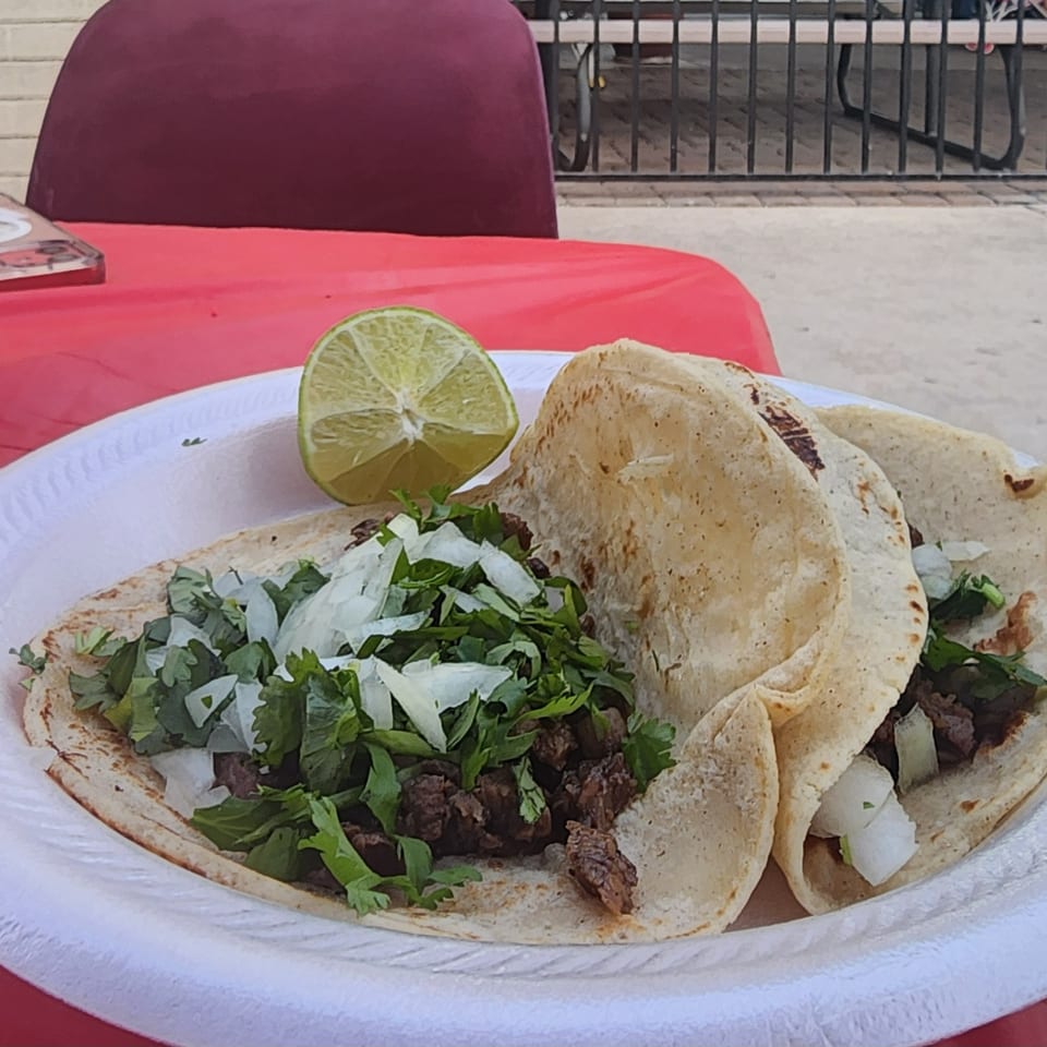 Three Don Pancho Mexican Food tacos with meat, cilantro, onions, and a lime wedge on a white plate.
